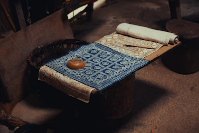 Traditional unstitched cloth with intricate thread work laid out on a wooden table.