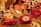 A festive arrangement featuring wrapped gifts in various metallic and festive colors, including red and gold. The centerpiece is a wrapped item labeled 'Authentic Panettone.' Surrounding it are other wrapped gifts and a bottle of champagne, creating a celebratory and luxurious atmosphere.