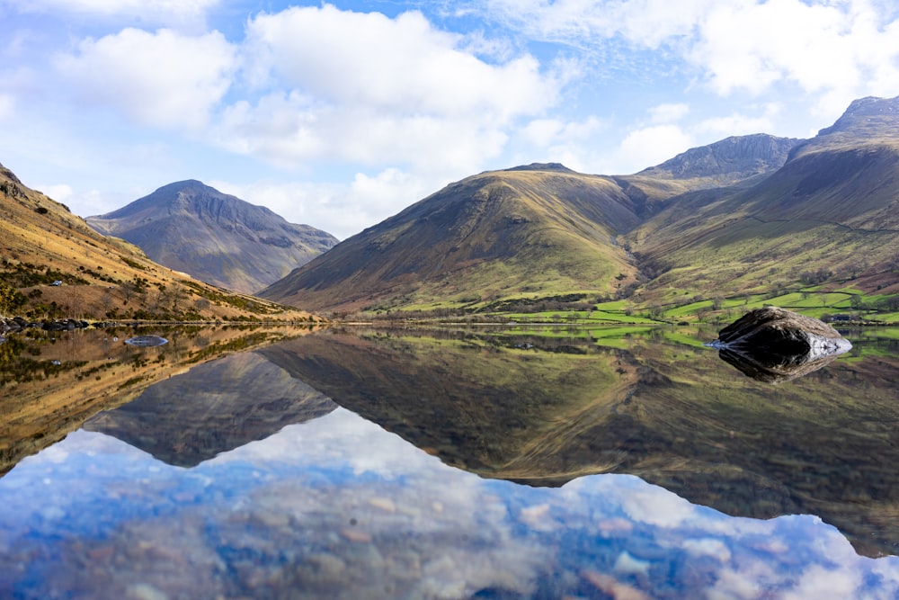 a lake surrounded by mountains with a reflection in the water