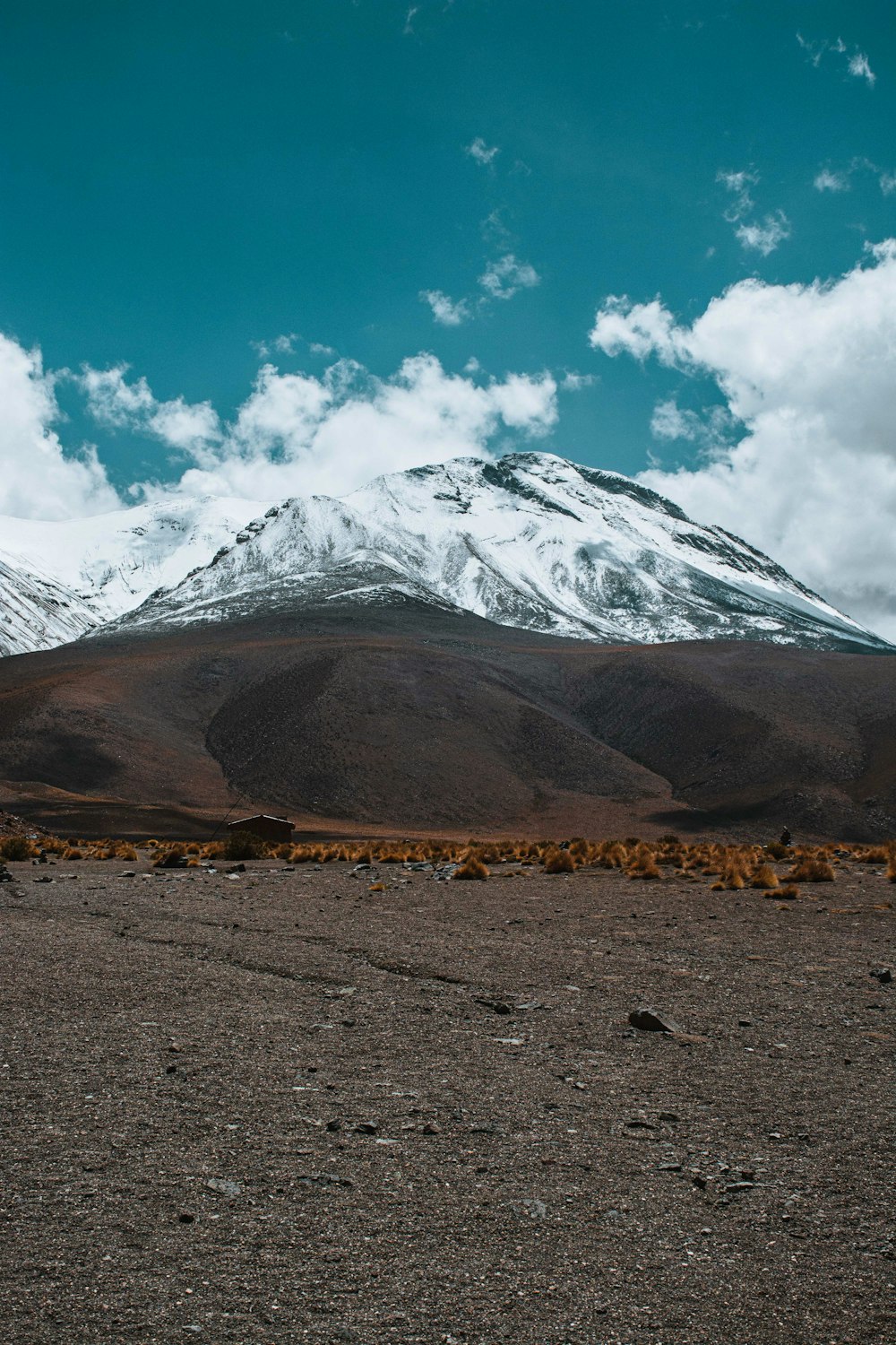 a snow covered mountain in the distance with a few clouds in the sky