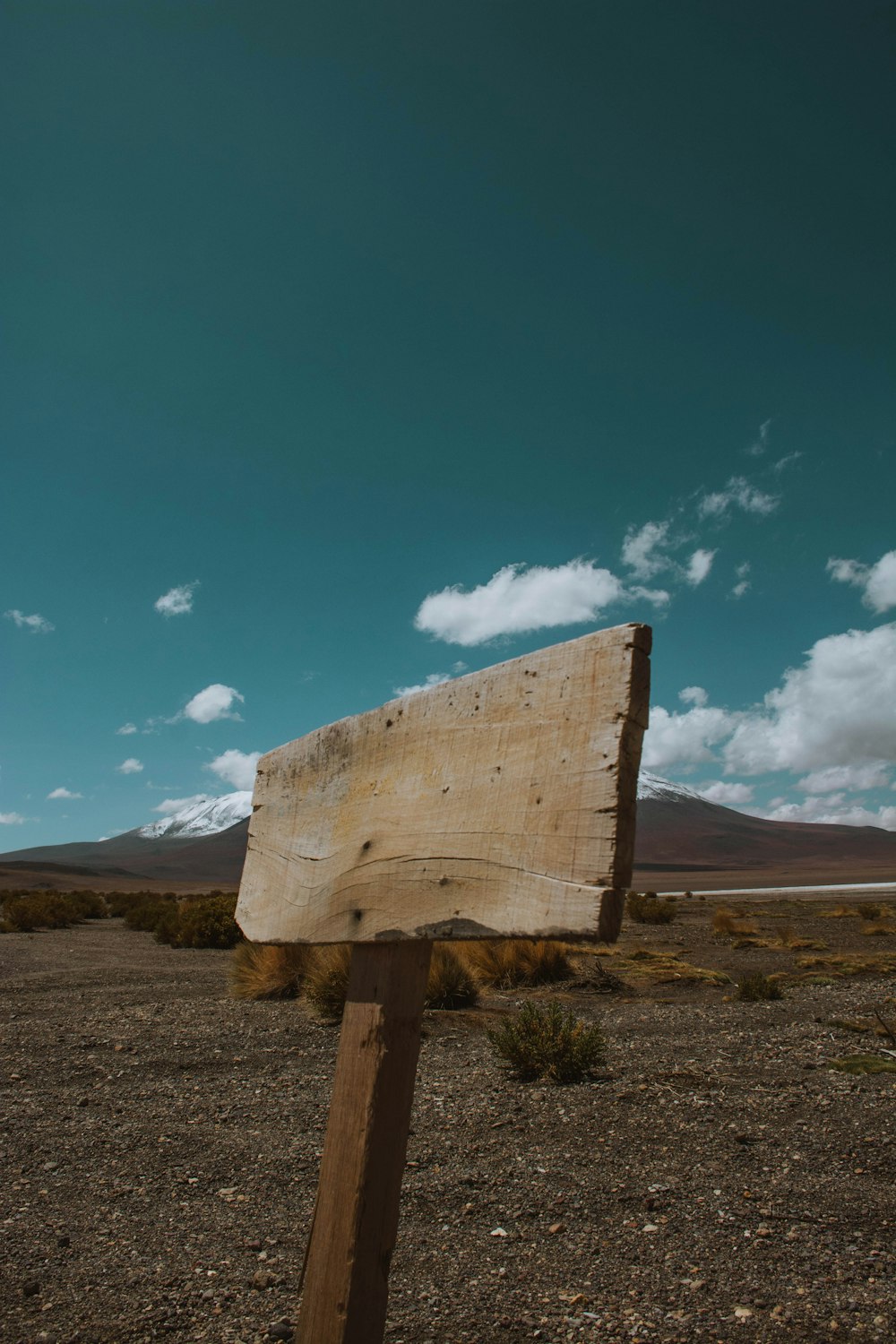 um sinal de madeira sentado no meio de um deserto