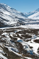 A panoramic view of Uttarakhand’s rugged mountains under a clear blue sky, with a winding river below