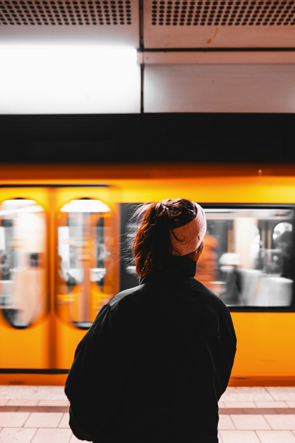 a person standing in front of a yellow train