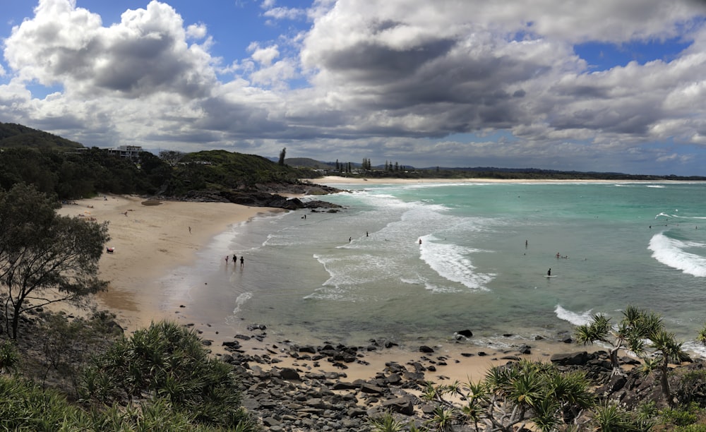 a sandy beach with people swimming in the water