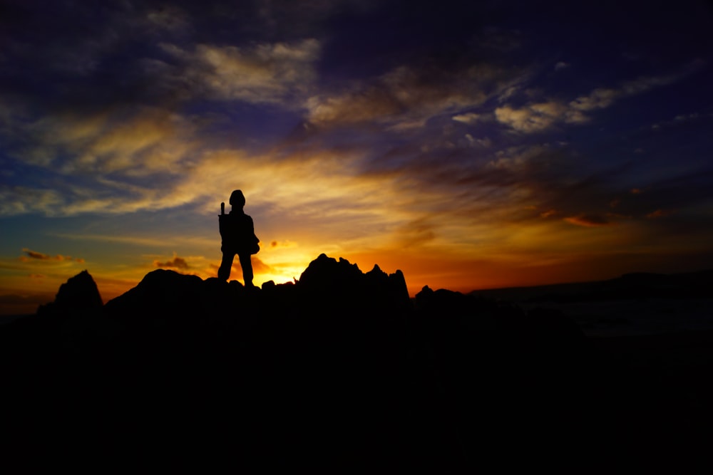 a person standing on top of a mountain at sunset