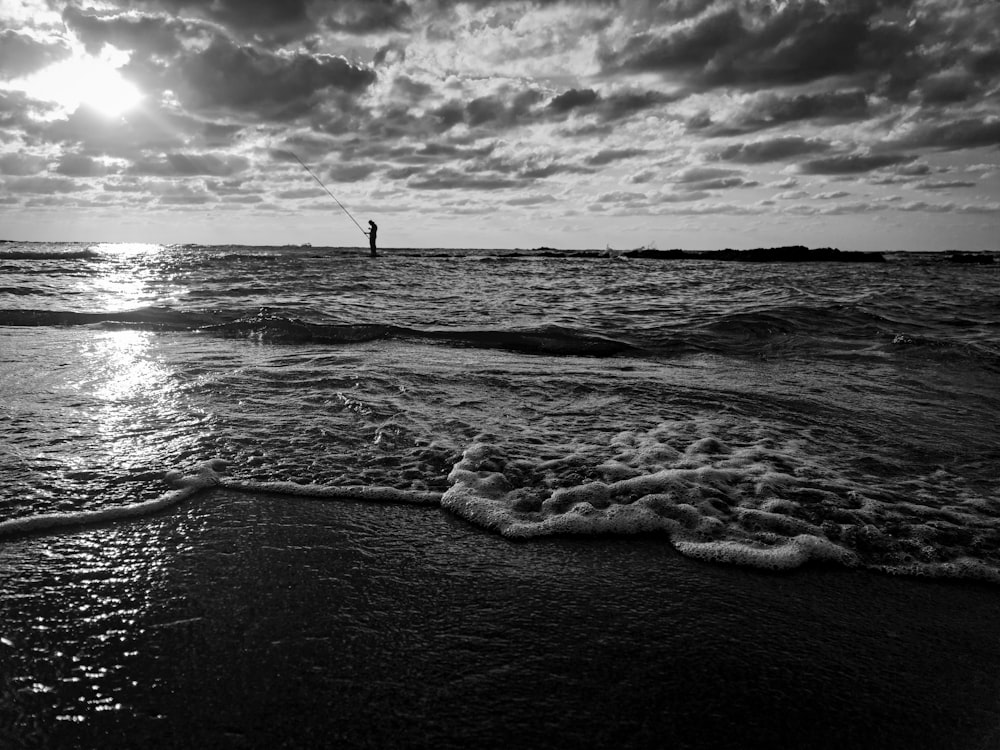 a black and white photo of a person standing in the ocean