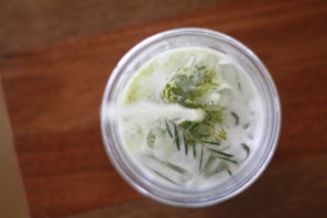 A refreshing matcha bubble tea served in a clear cup with whipped cream on top.