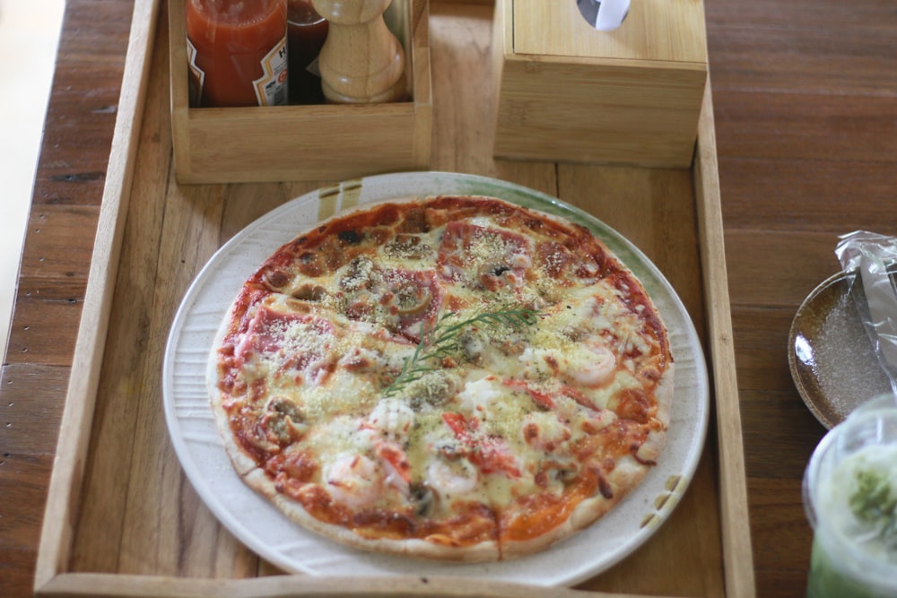 a pizza sitting on top of a white plate on a wooden tray