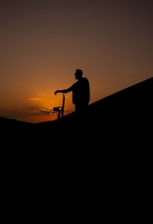 a man riding a bike down a hill at sunset
