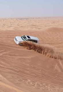 a car driving through the desert in the sand