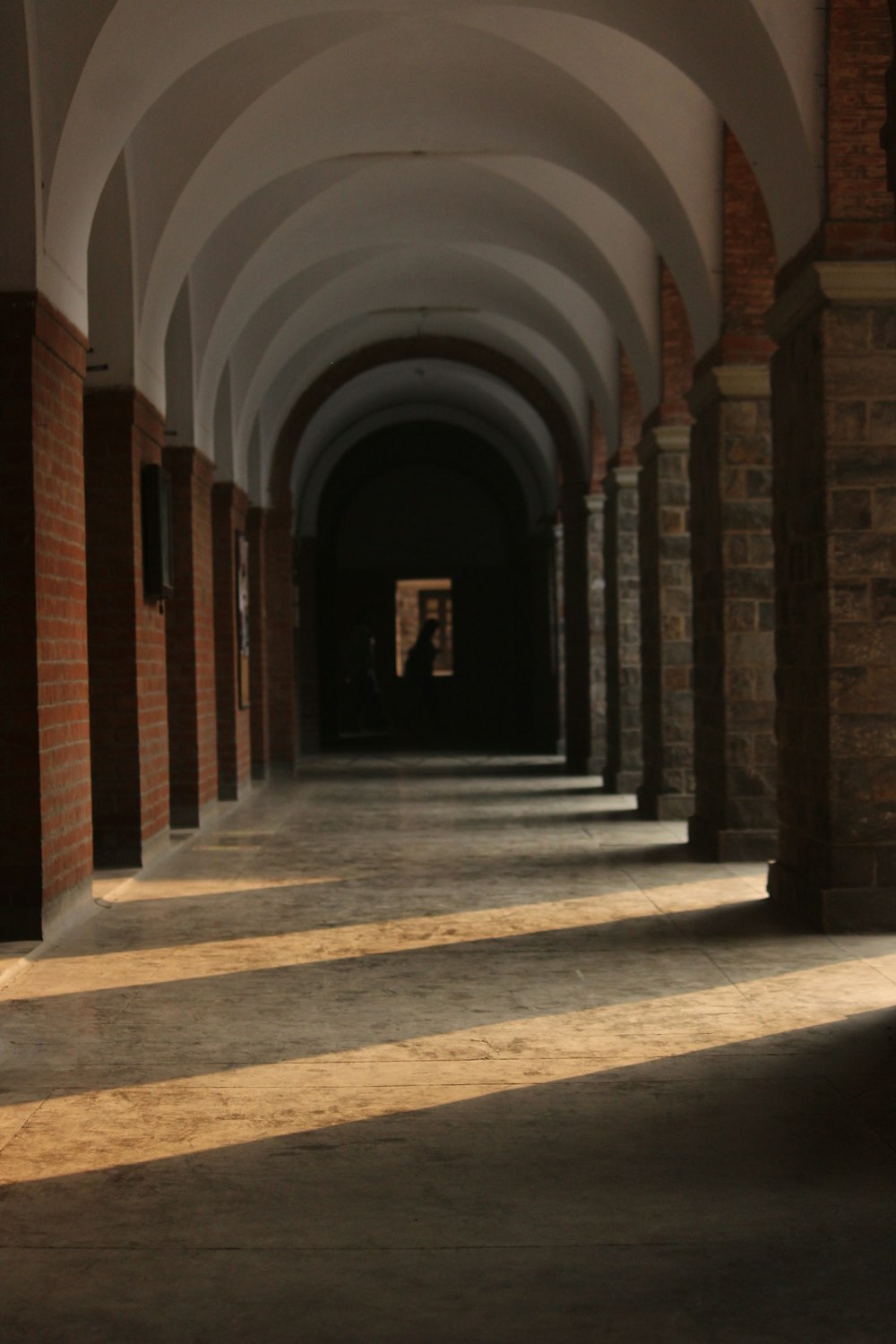 a long hallway with arches and a clock on the wall