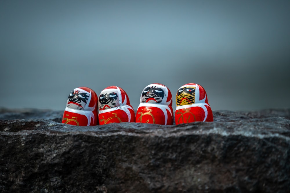 a group of red and white dolls sitting on top of a rock
