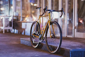 A sleek modern electric bike parked by a city sidewalk at sunset.