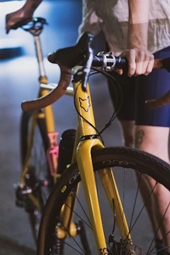 Close-up of a rider’s hands gripping handlebars with vibrant safety orange gloves under neon streetlights.