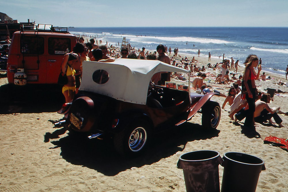 a beach filled with people and an old car