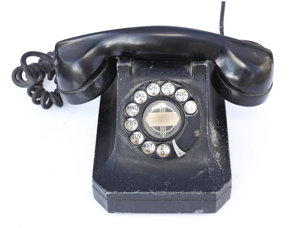 Un viejo teléfono negro con botones y un cable