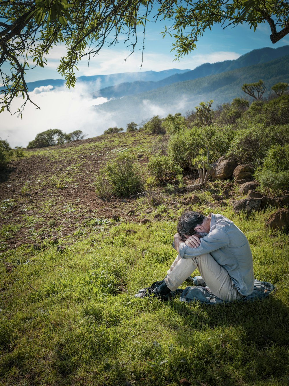 a man sitting on the ground with his head in his hands