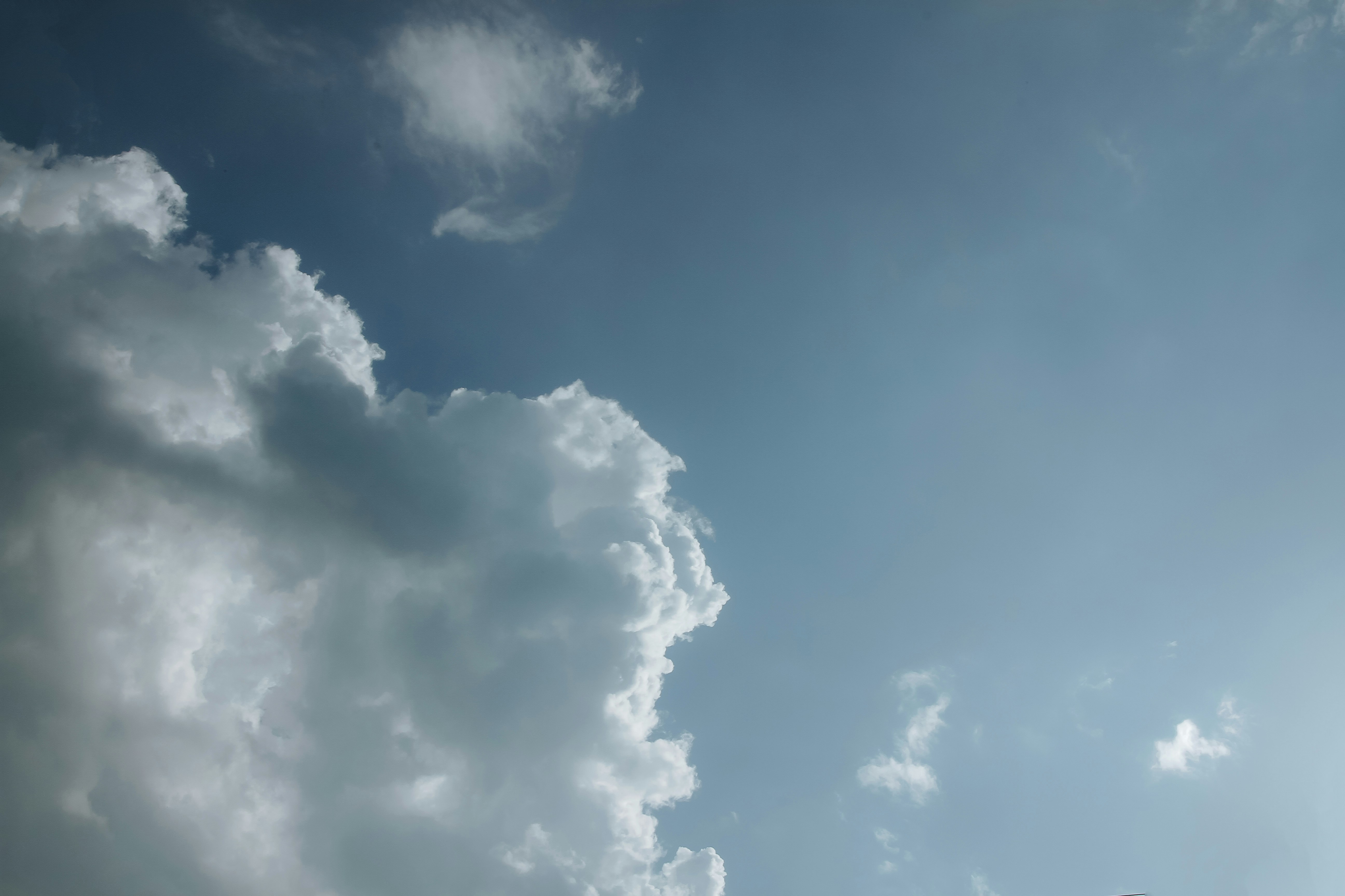 a plane flying through a cloudy blue sky