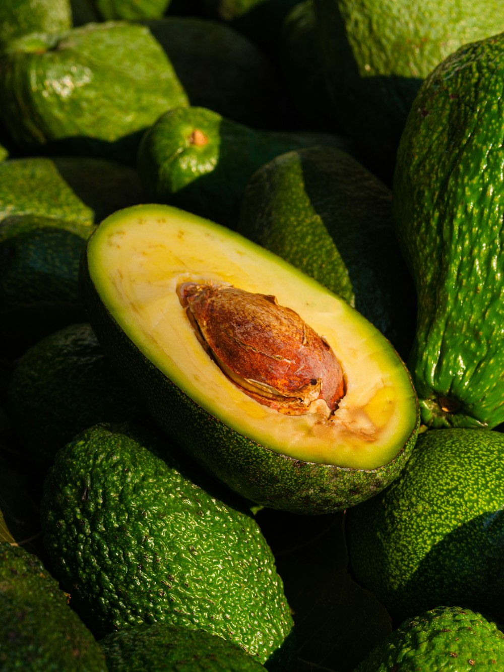 Un montón de aguacates verdes sentados uno encima del otro