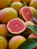 a pile of grapefruits with one cut in half