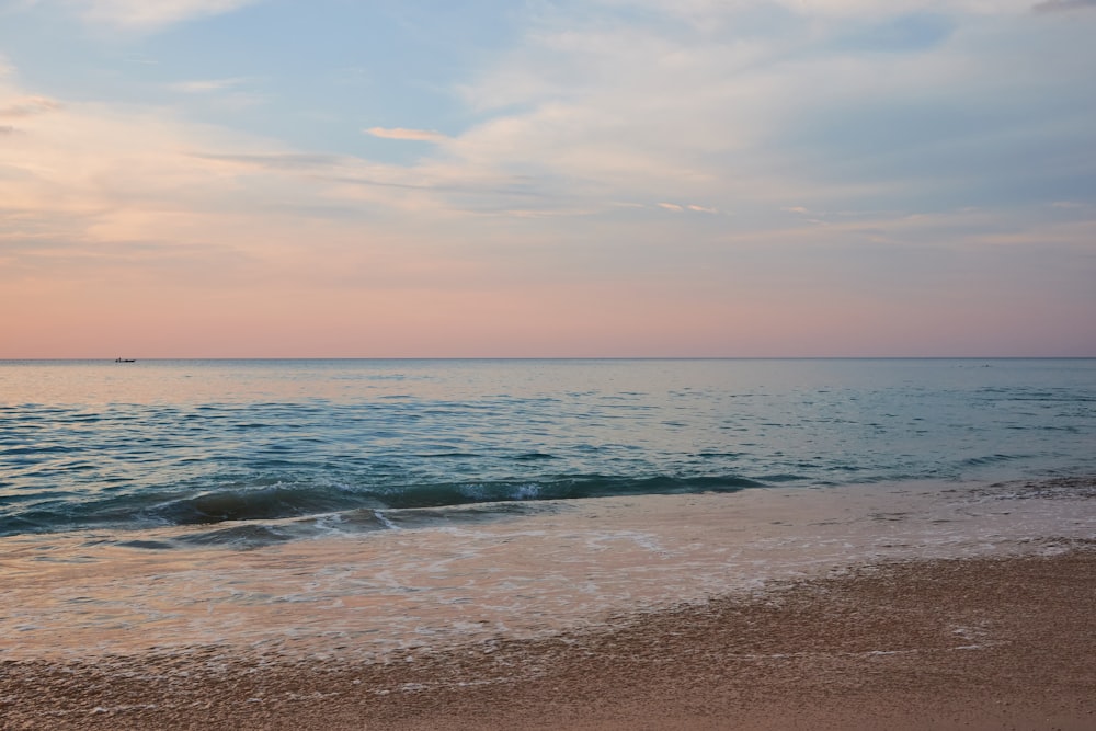 a view of the ocean from a beach at sunset