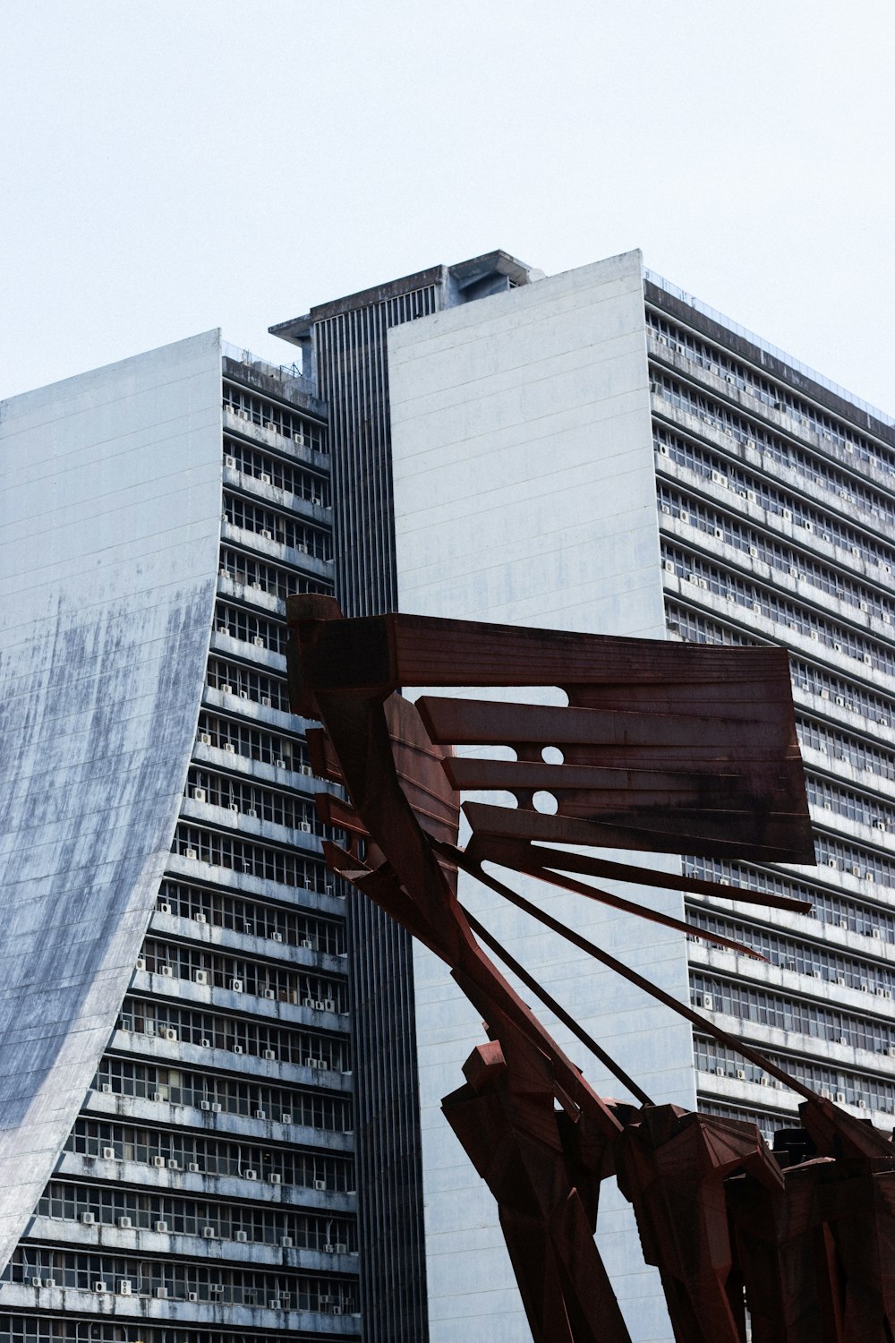 uma grande escultura de metal na frente de um edifício alto