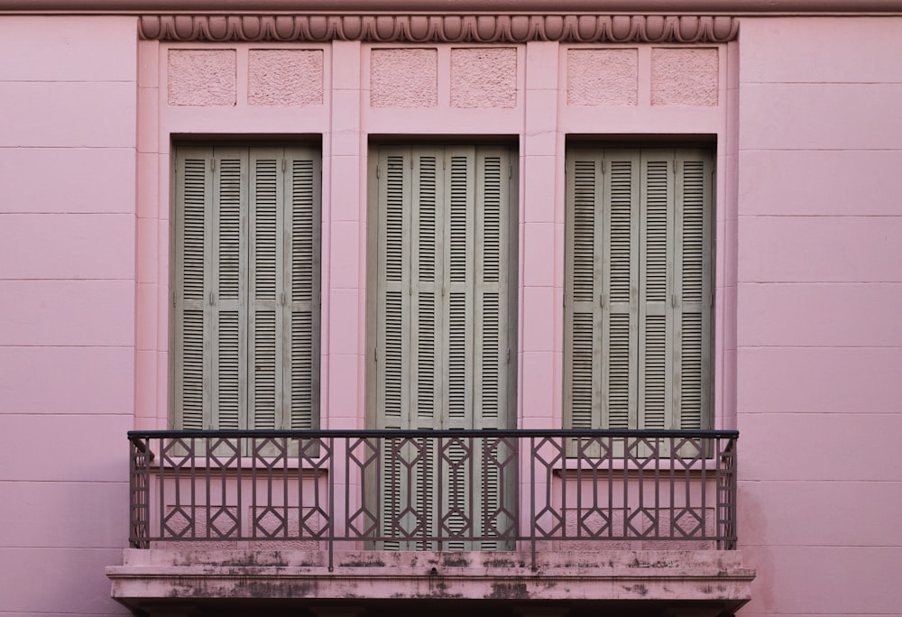 2つの窓とバルコニーのあるピンクの建物
