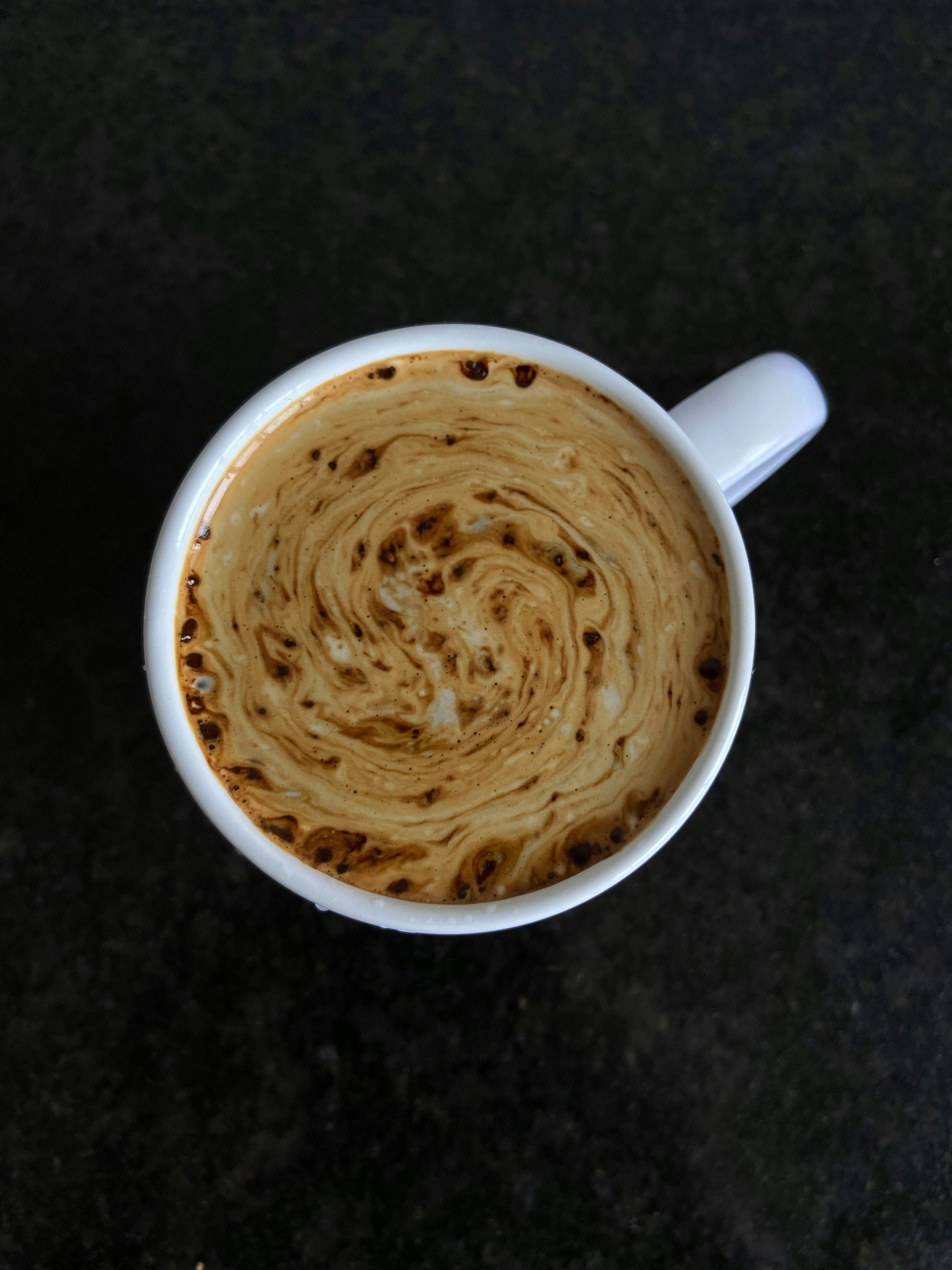 Close-up of a steaming cup of coffee with swirling cream, capturing the science of mixing liquids.
