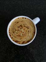 Close-up of a steaming cup of coffee with swirling cream, capturing the science of mixing liquids.