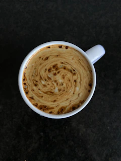 Macro shot of swirling coffee vapor rising delicately from a dark ceramic cup