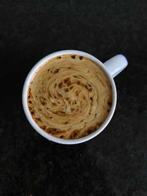 Close-up of a steaming cup of coffee with swirling cream, capturing the science of mixing liquids.