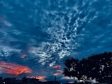 Dramatic sky with deep blue tones and volumetric clouds over unchanged foreground.