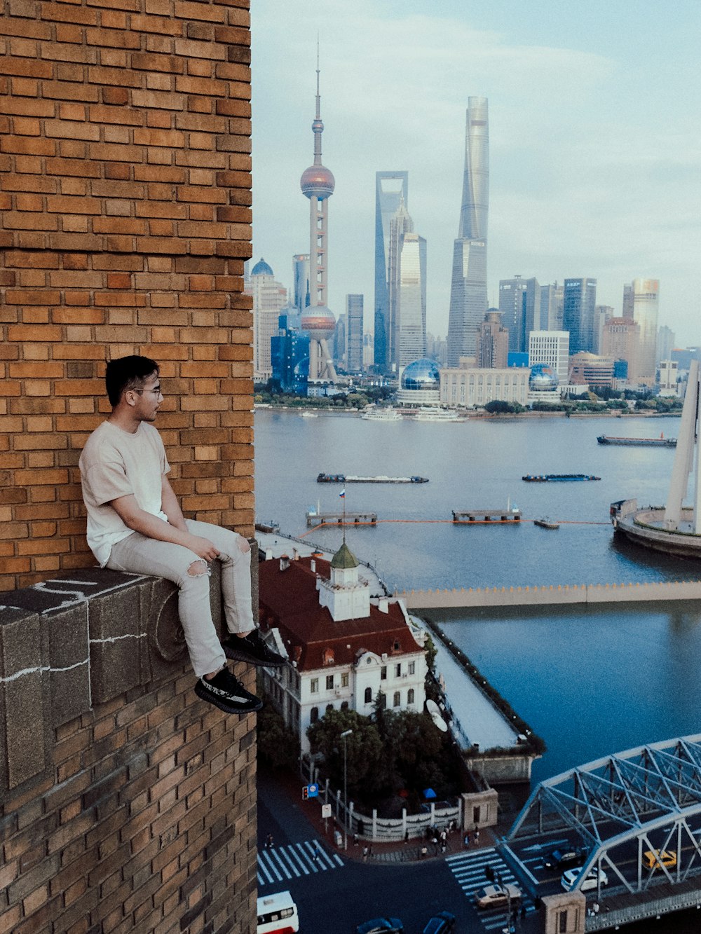 a man sitting on a ledge overlooking a city