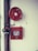 A fire safety setup featuring a red fire hose reel mounted on a wall alongside a rectangular red metal cabinet containing a fire hose and nozzle. Pipes and a valve are visible, highlighting the system's functionality.