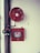 A fire safety setup featuring a red fire hose reel mounted on a wall alongside a rectangular red metal cabinet containing a fire hose and nozzle. Pipes and a valve are visible, highlighting the system's functionality.