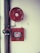 A fire safety setup featuring a red fire hose reel mounted on a wall alongside a rectangular red metal cabinet containing a fire hose and nozzle. Pipes and a valve are visible, highlighting the system's functionality.