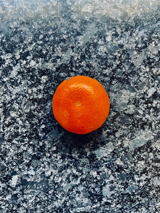 A vibrant orange gadget against a matte graphite background.