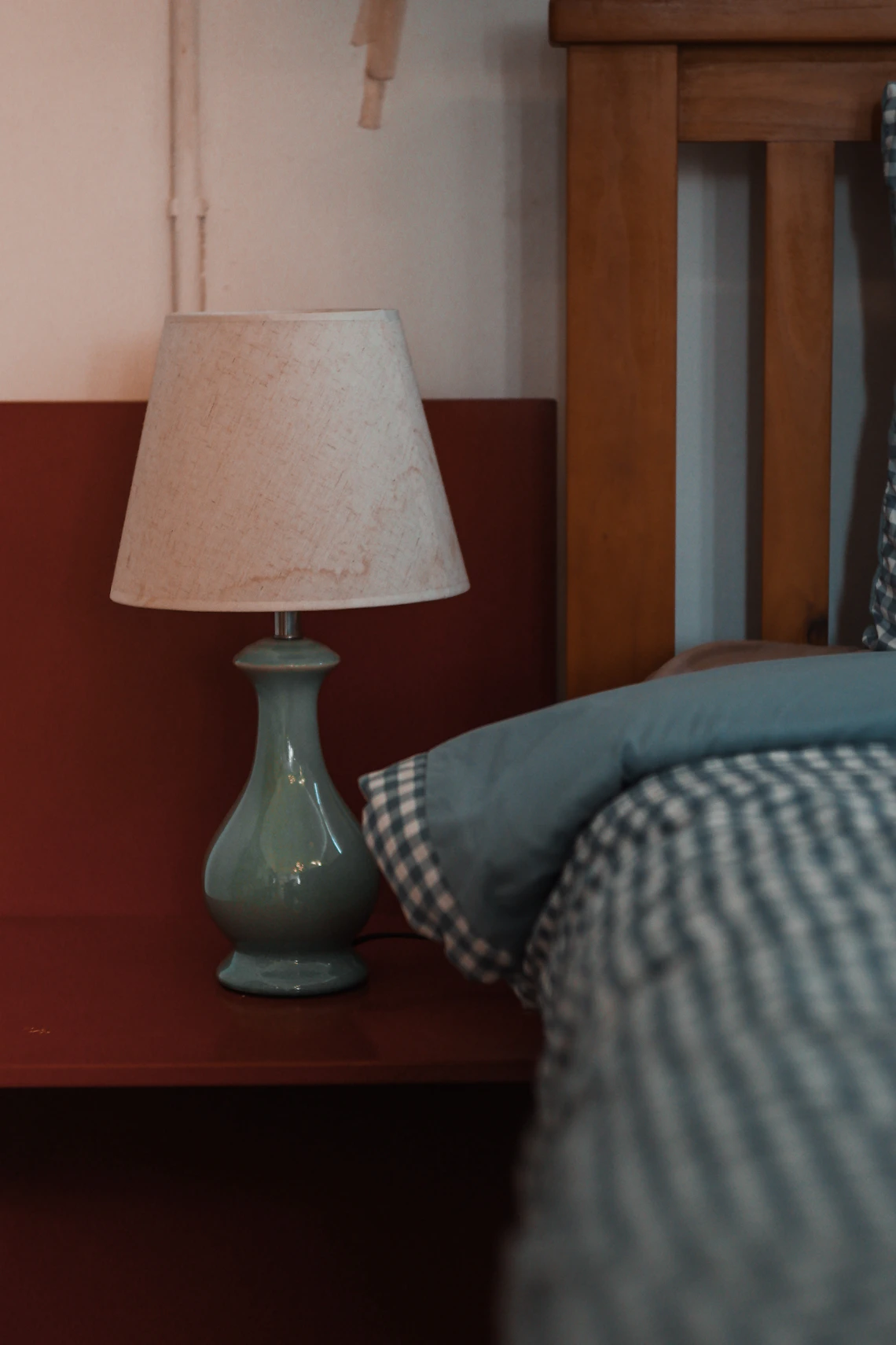 Real bedroom interior with a bedside lamp, bed, pillows, and warm wood furniture