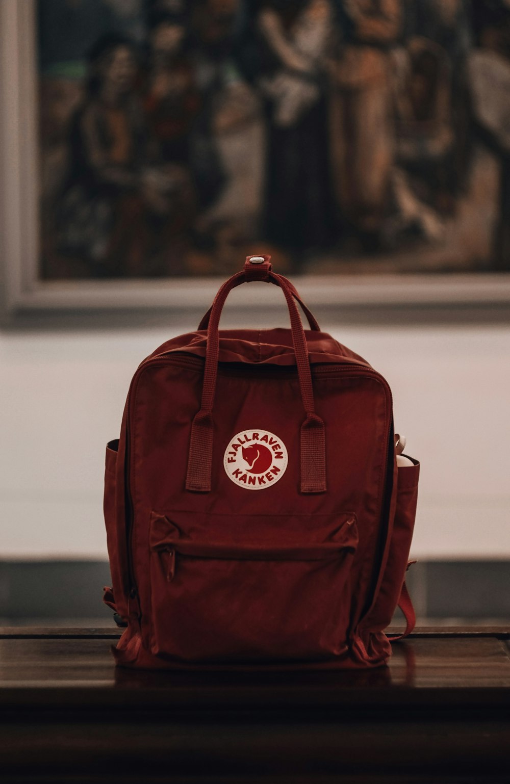 a red backpack sitting on top of a wooden table