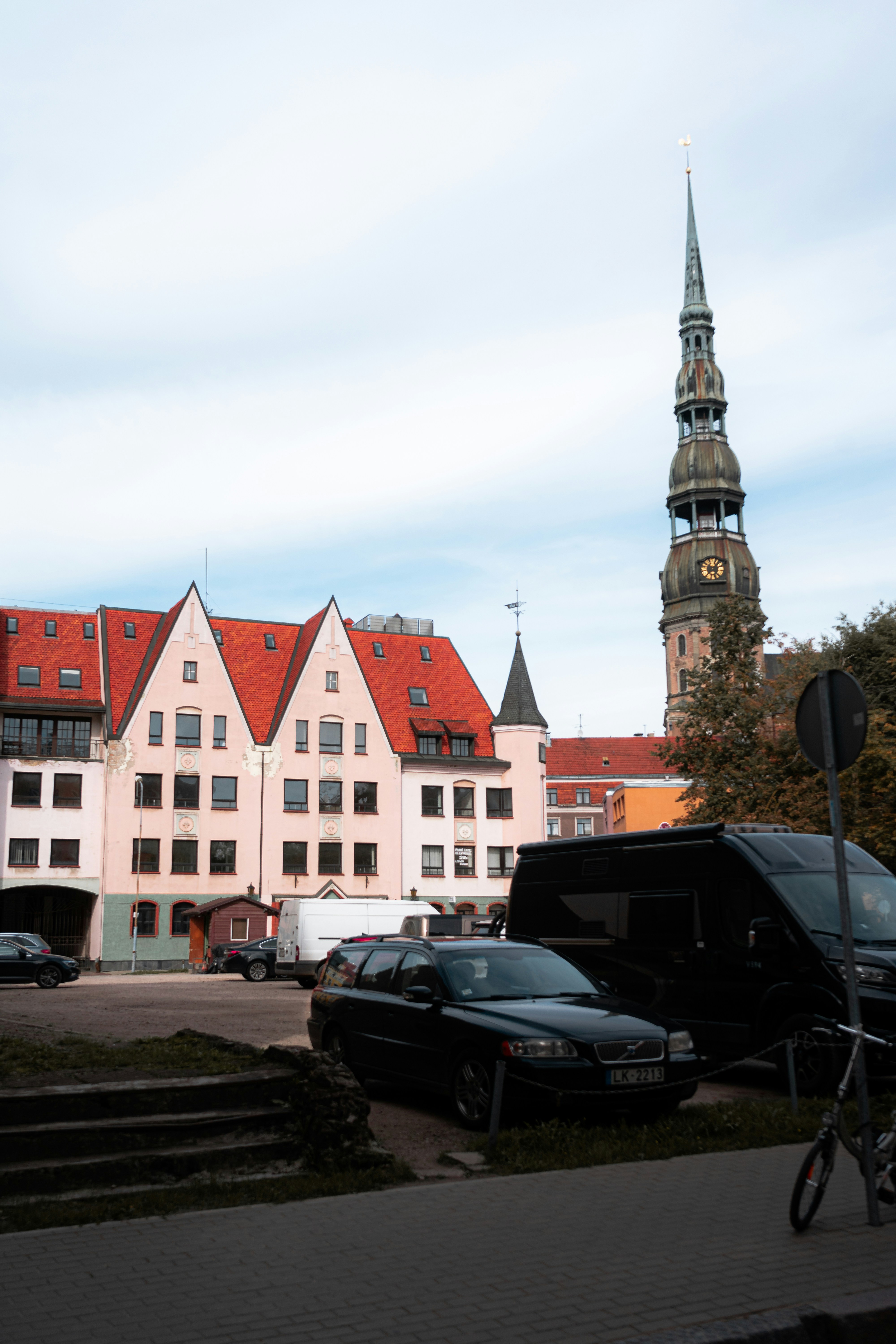 cars parked in front of a building with a clock tower in the background