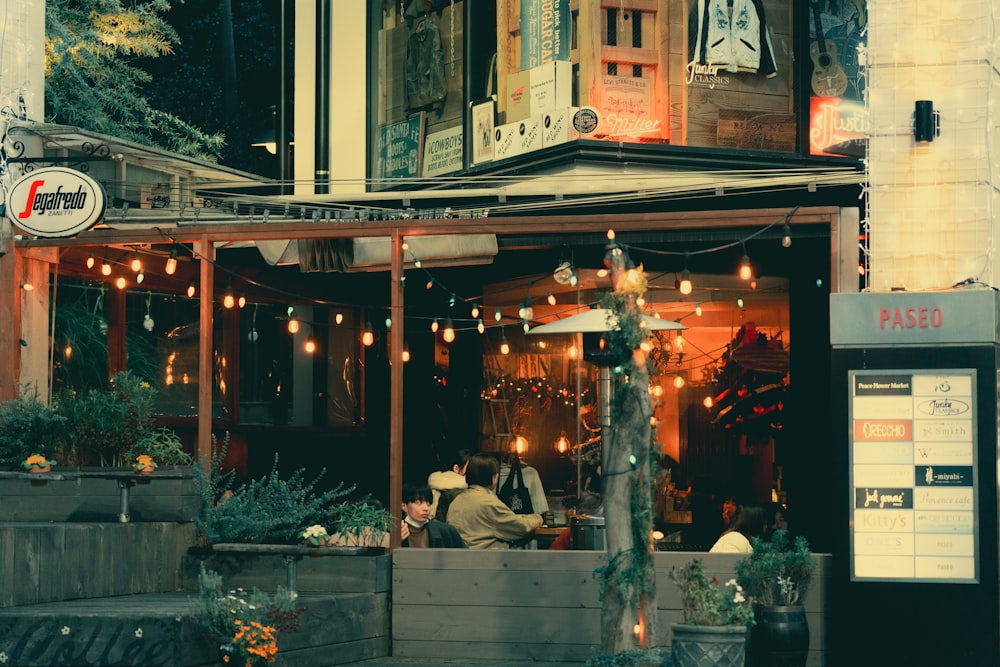 a couple of people sitting at a table outside of a restaurant