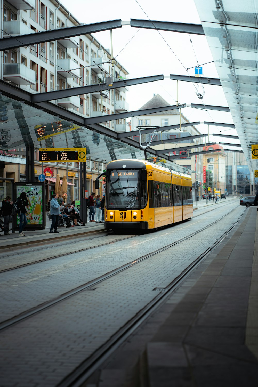 a yellow train traveling down train tracks next to a tall building