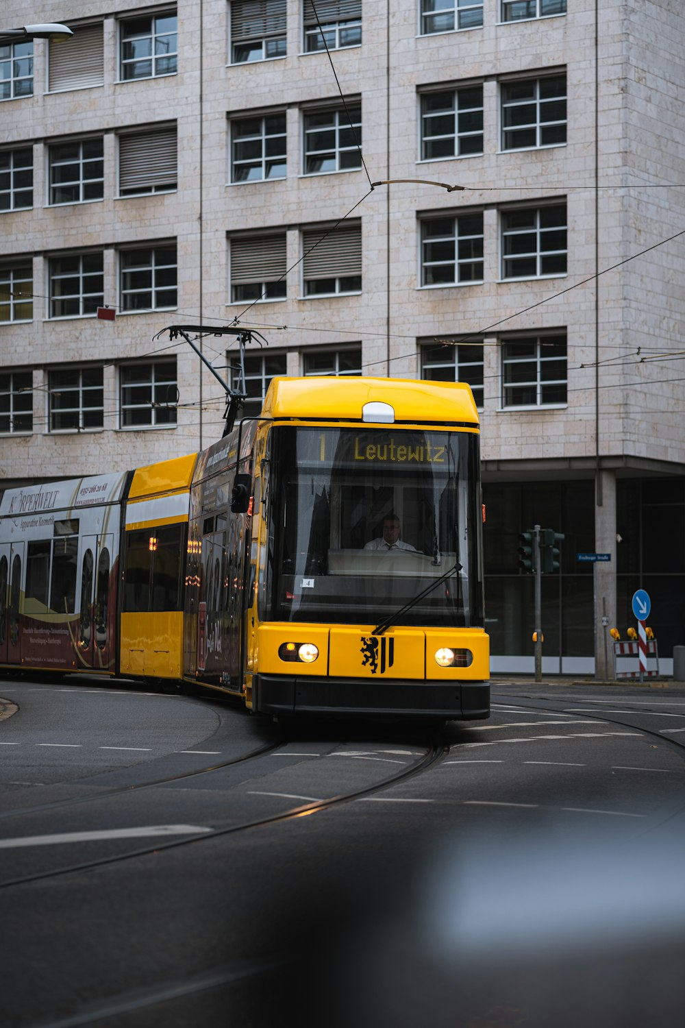 a yellow bus driving down a street next to a tall building