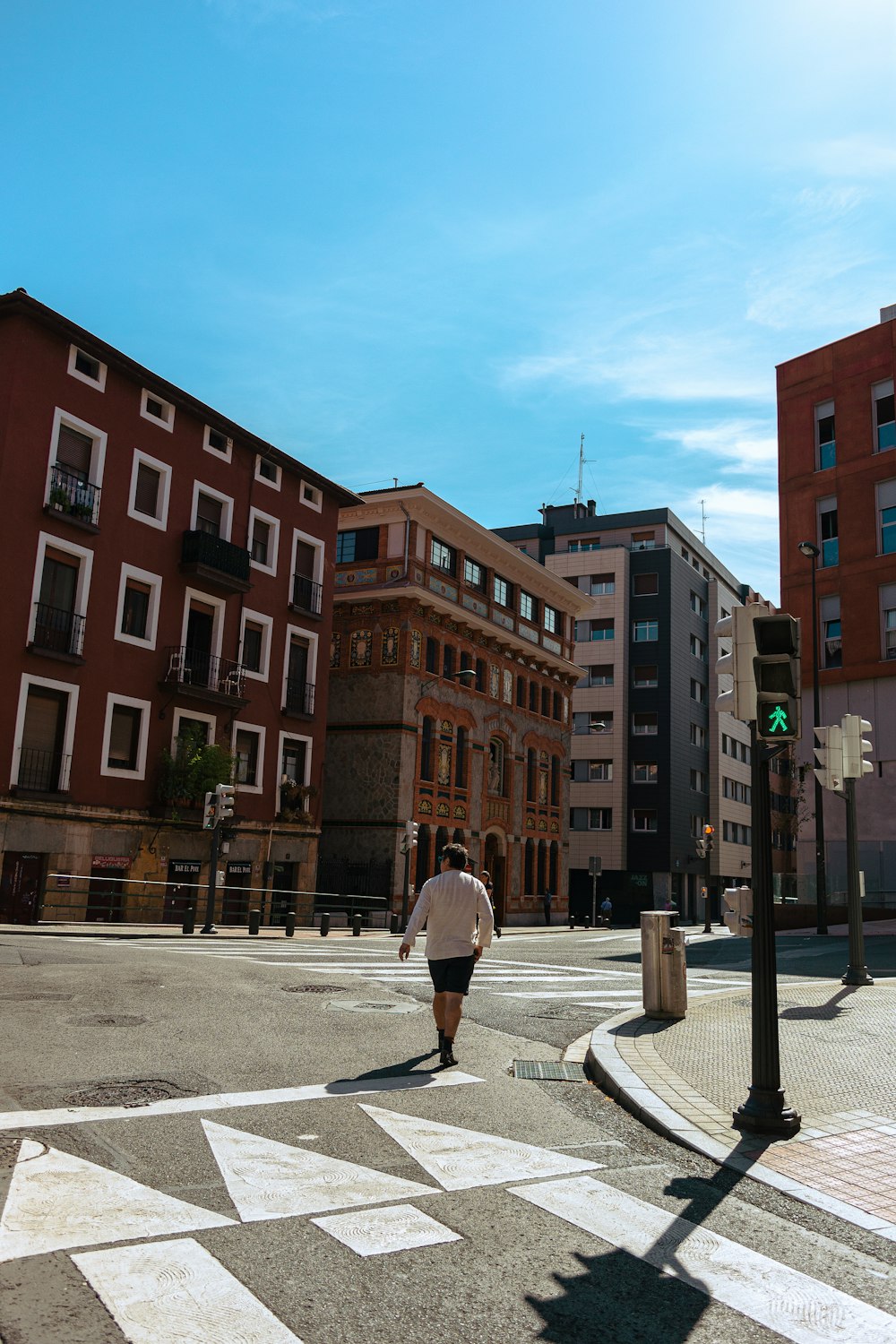 a man walking across a cross walk in a city