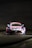 A race car is prominently displayed against a dark background. The vehicle is primarily pink, blue, and white, featuring branding from 'BWT' and 'AUTOHERO' on the hood and windshield. The car has a distinctive aerodynamic design typical of racing cars, with a prominent front grille and sleek headlights. Mercedes-Benz and Michelin logos are also visible on the car.