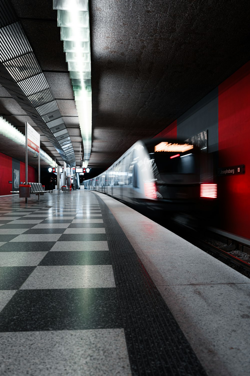 a train traveling through a train station next to a checkered floor