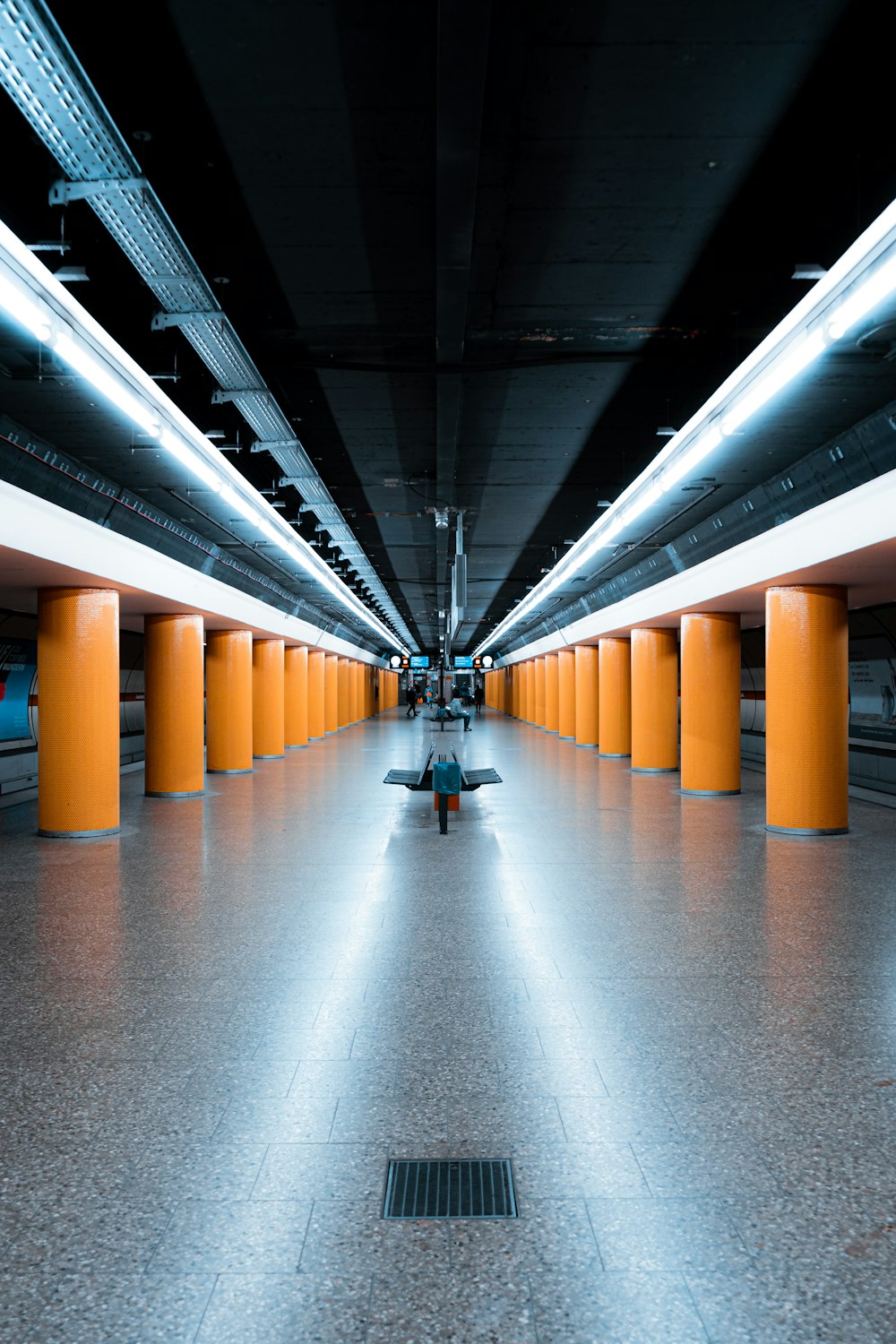 a long hallway with yellow pillars and a bench