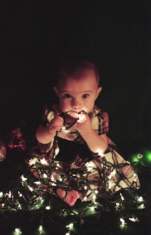 Close-up of a toddler playing joyfully under warm fairy lights in a cozy nursery.