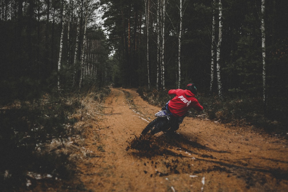 a man riding a dirt bike down a dirt road