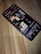 A smartphone is lying on a wooden surface, displaying a music streaming app that shows playlists and songs on the screen.